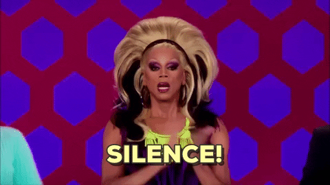 RuPaul en drag queen frappe dans ses mains et réclame le silence