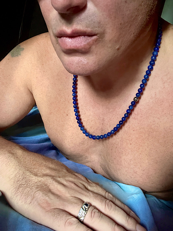 Orpheus allongé sur le lit avec un collier de perles bleues autour du cou