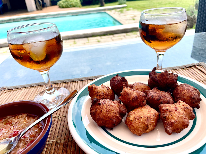 Assiette d’accras sur la table du salon de jardin accompagné d’un verre de Mascatel Ambré et une coupelle de sauce créoline