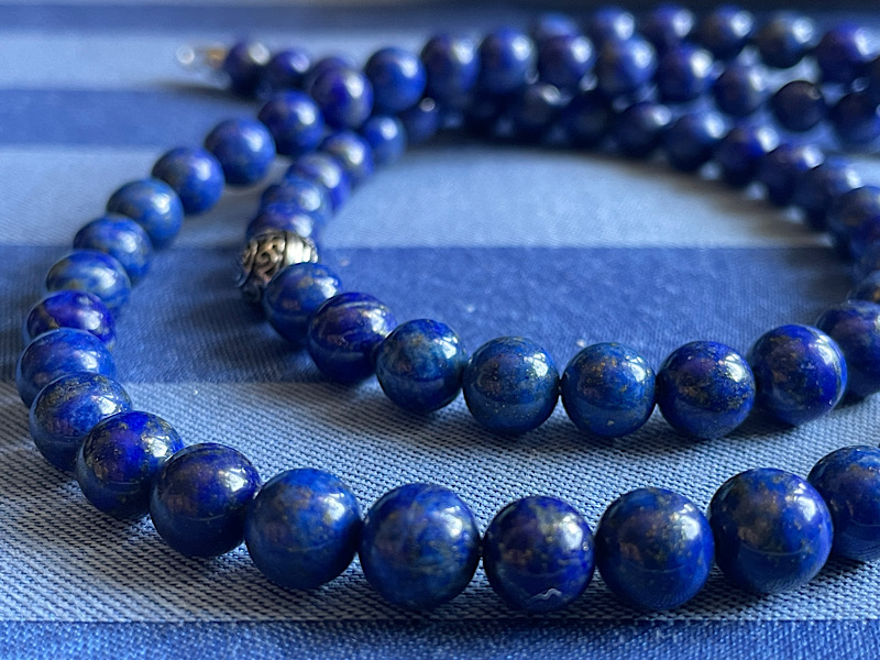 Un collier de perles bleues enroulé et posé sur la table du salon