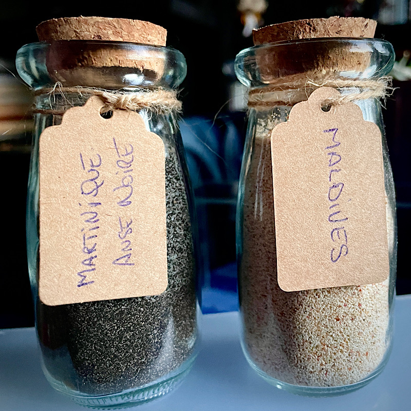 2 fioles, l’une avec du sable noir de martinique, l’autre avec du sable blanc des Maldives