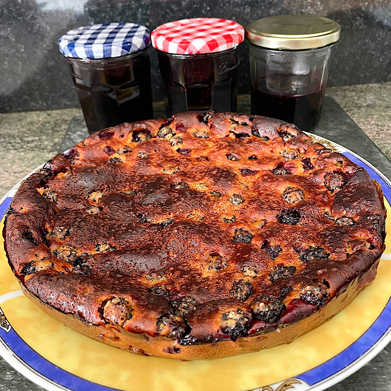 Un clafoutis devant 3 pots de confiture de mûres dont 1 rempli à motié