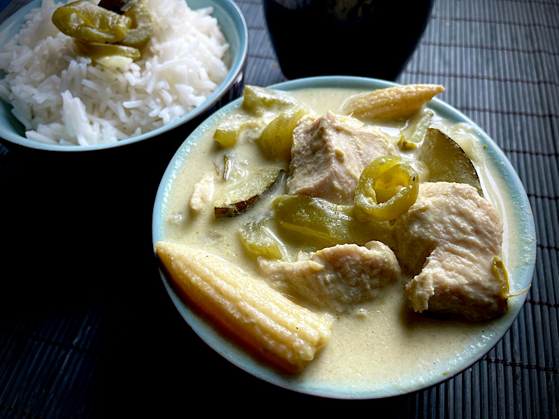 Un bol de chicken grenn curry, un bol de riz, un verre de vin